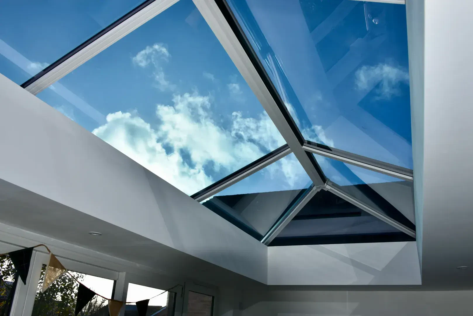Close-up of an orangery roof lantern with blue sky visible through black and white glazing bars.