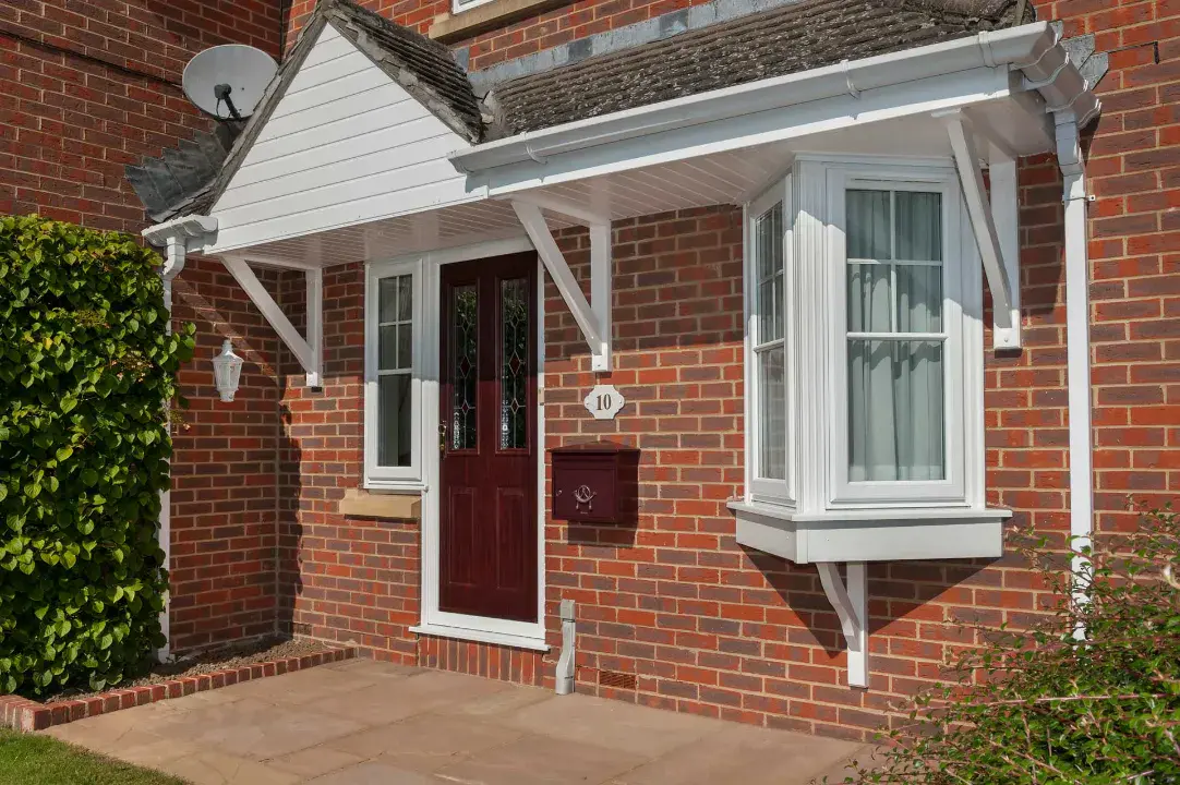 Red uPVC entrance door with decorative glazing fitted to a brick home