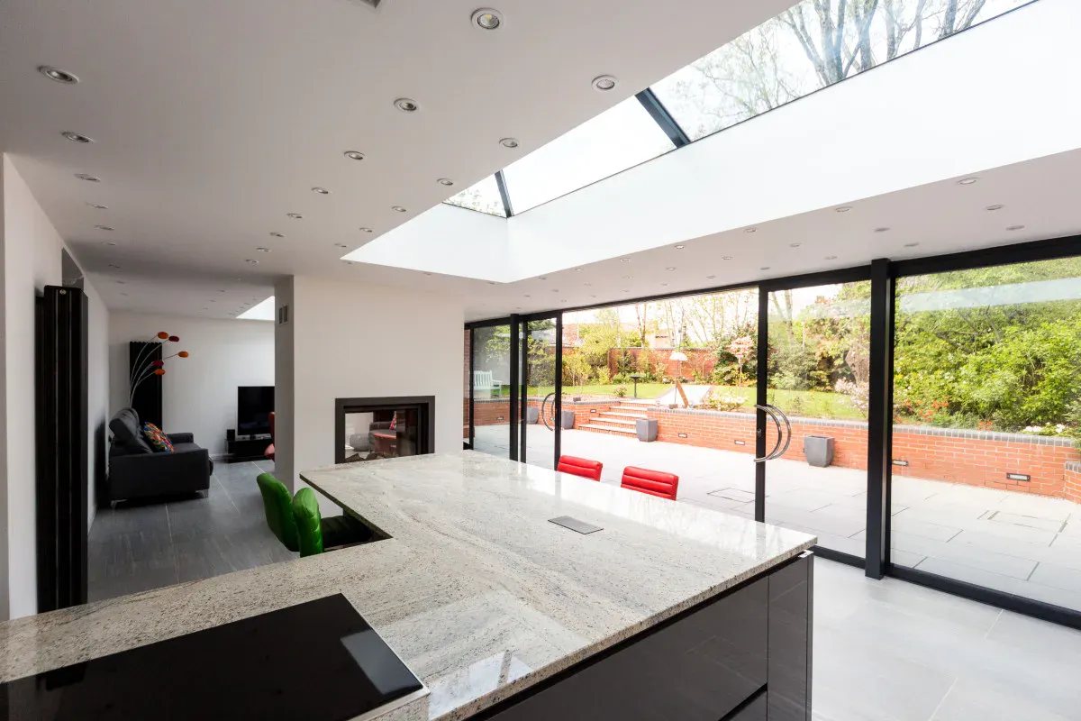 Modern kitchen extension with black sliding patio doors, rooflights, large island and garden views.