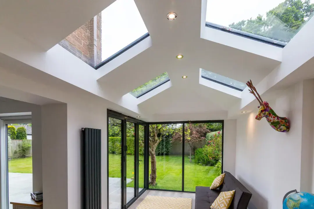 Solid roof conservatory interior with roof lights, dark sliding doors, garden views and a sofa area.