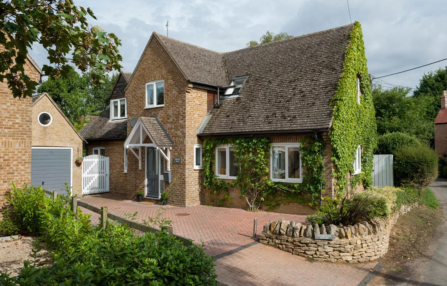 White uPVC casement windows fitted to an ivy-covered brick cottage
