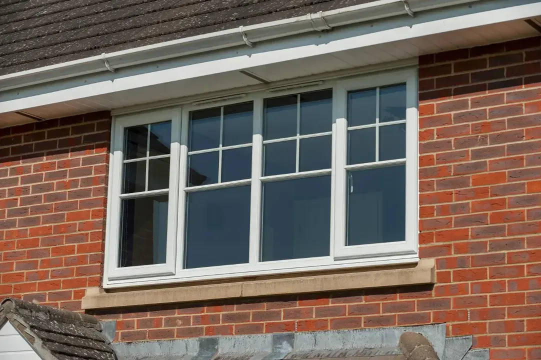 White sliding sash window with Georgian bars fitted to a red brick property