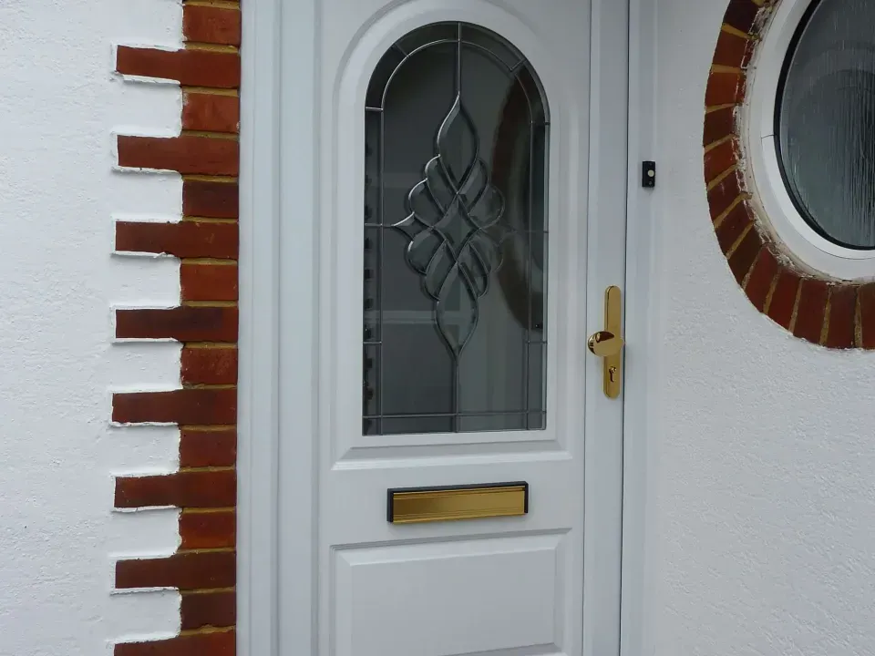 White uPVC entrance door with decorative glazing and gold hardware