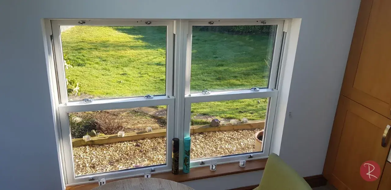 Interior view of white uPVC sliding sash windows overlooking a garden