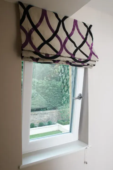White uPVC tilt and turn window with a patterned Roman blind