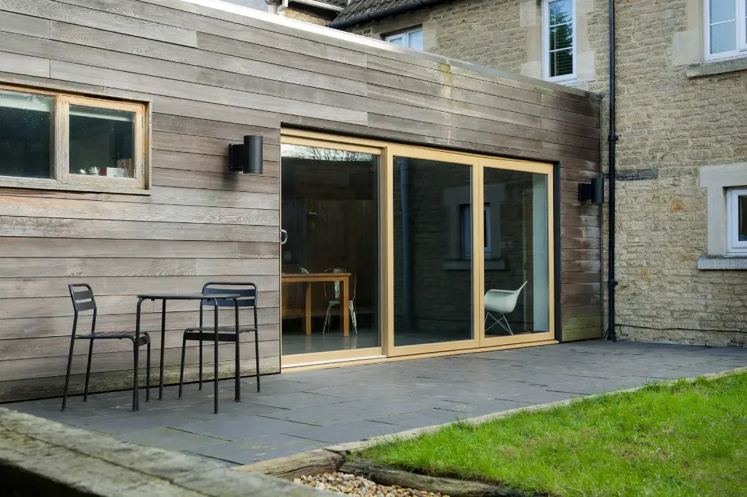 Wood-effect uPVC sliding patio doors fitted to a timber-clad extension