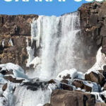 Waterfall cascading over rocks with icy surroundings in Iceland.