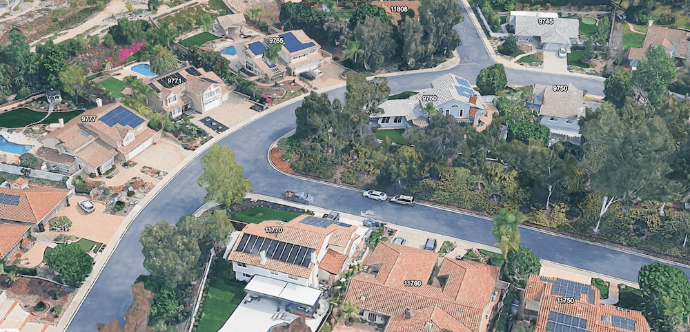 Aerial view of a quiet Scripps Ranch residential street with large homes, mature trees, curved roads, and rooftop solar panels in San Diego