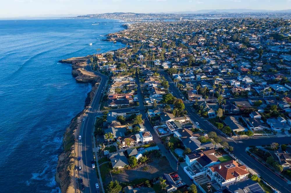 An aerial drone shot capturing the coastline and residential neighborhoods of San Diego, showcasing the beautiful coastal landscape.