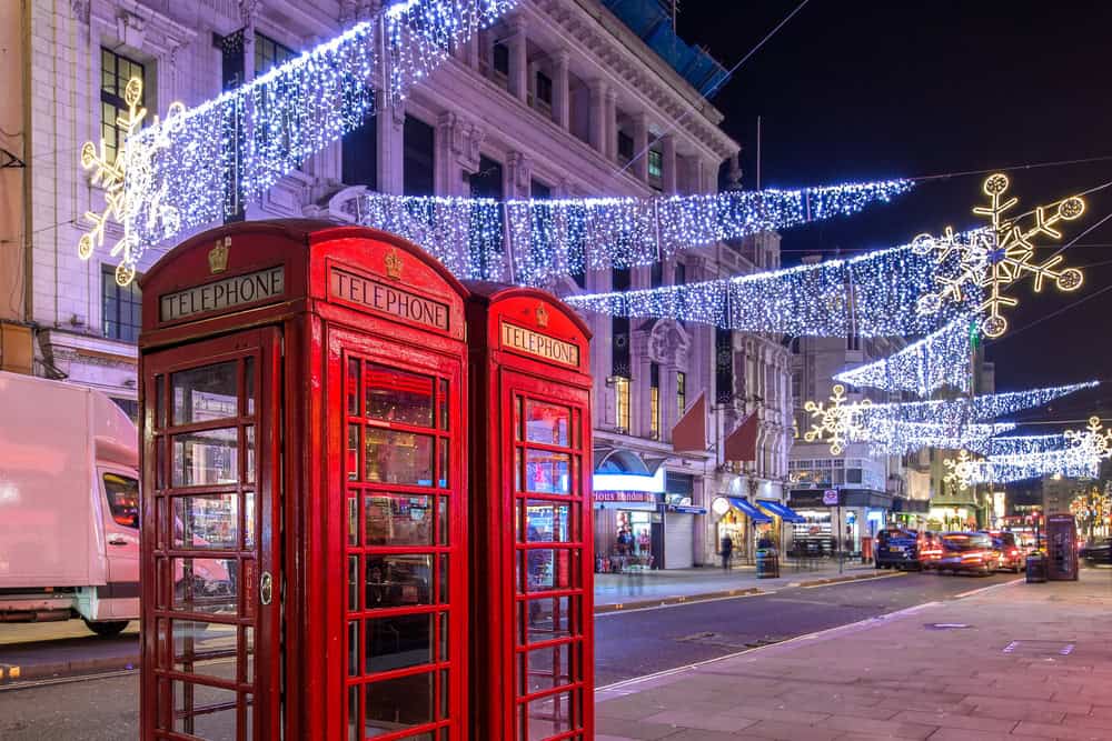 London highstreet with 2 red phone boxes and christmas lights