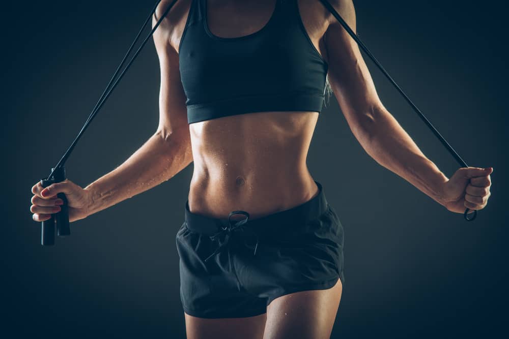 A woman exercising with black vest top and shorts