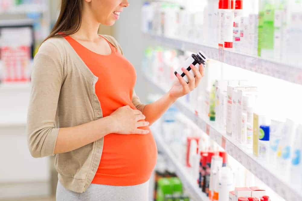 A pregnant woman in a chemist looking at medication