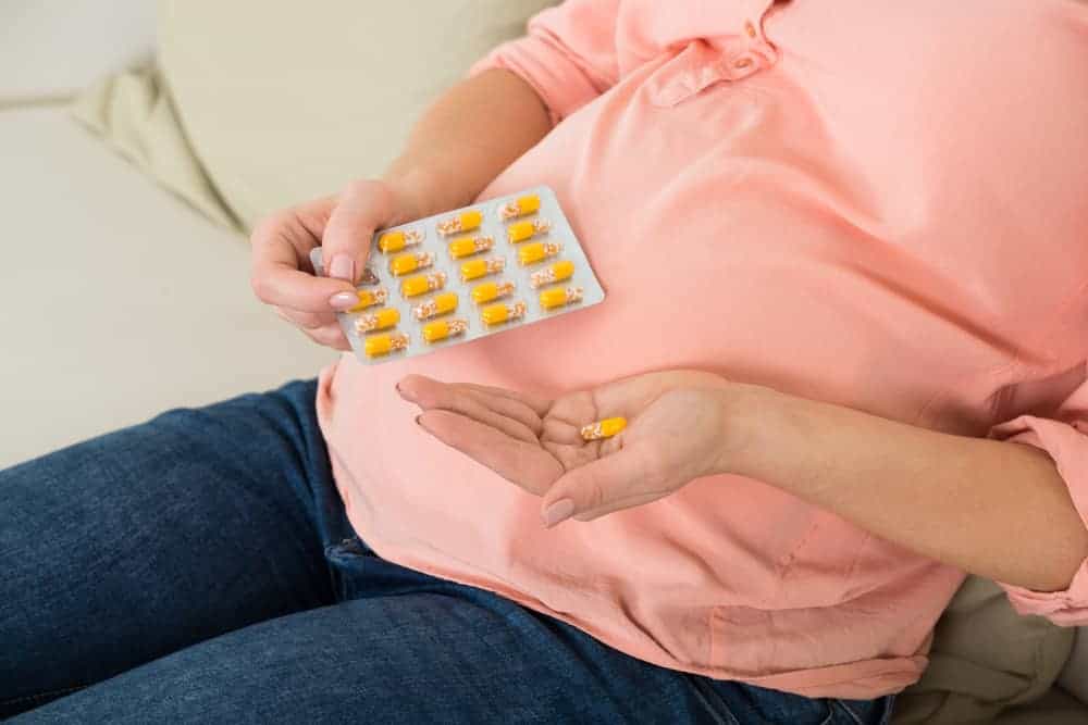 A person in a pink hoodie taking medication