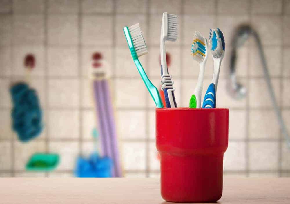Red toothbrush cup with four toothbrushes of different colours in.