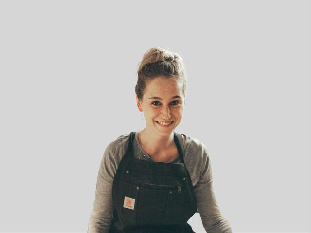 Frau mit Latzhose lächelt in die Kamera