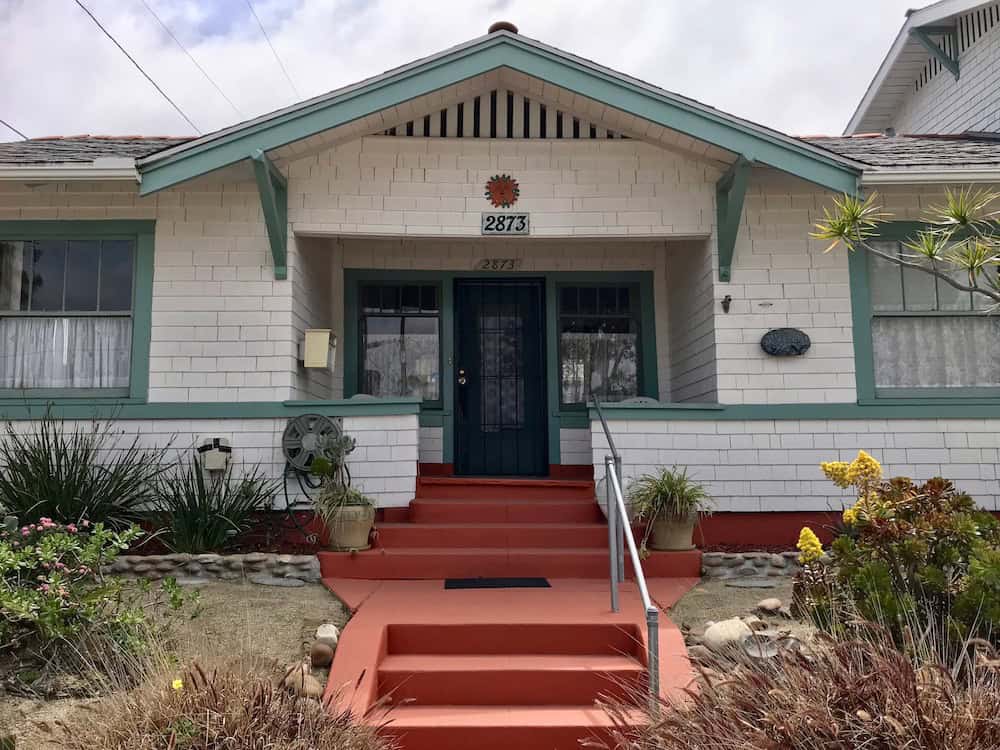 Historic white shingle Craftsman bungalow on Upas Street in North Park featuring teal trim, terracotta-colored steps, and drought-tolerant landscaping.