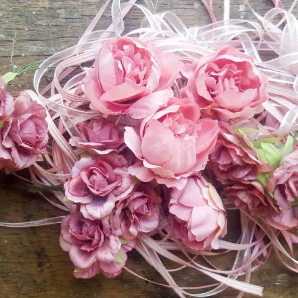 A collection of faux flowers and ribbons to adorn the broom Christmas tree #broomrepurpose #broomchristmastree #acraftymix #broomdecor #christmastree #DIYChristmasTree