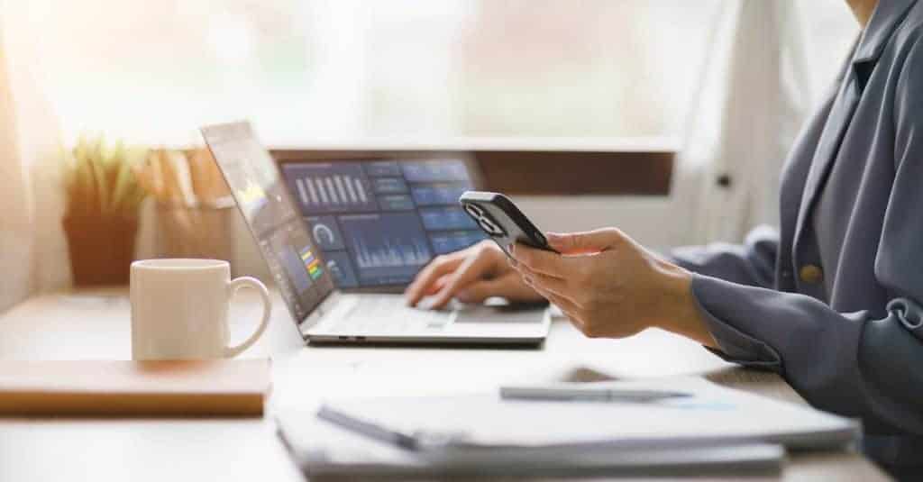 Personne utilisant un smartphone et un ordinateur pour la gestion de projets avec beCAD.