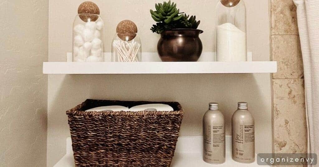 Shelves on a bathroom wall with bottles, jars and a basket