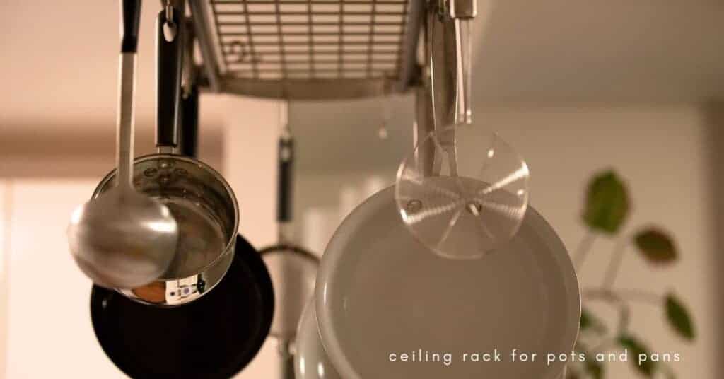 Pots and pans hanging from a ceiling rack in a kitchen