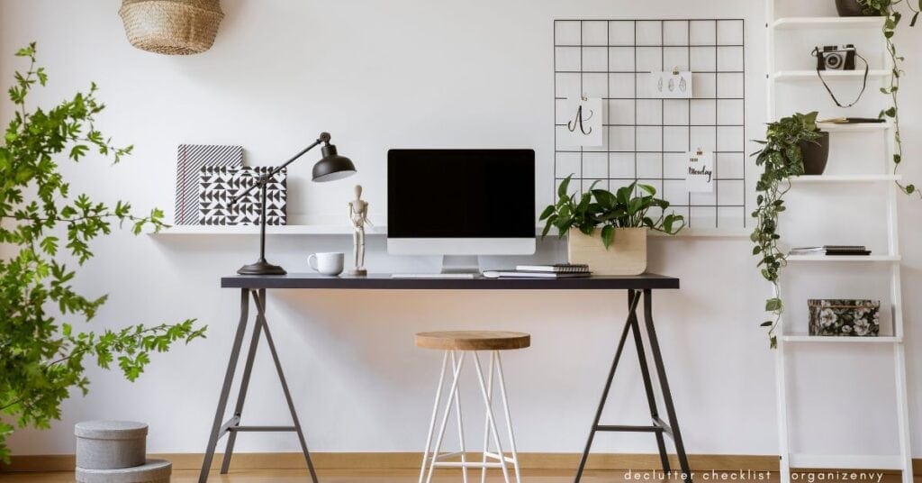 A small home office with a streamlined desk, computer and white shelves