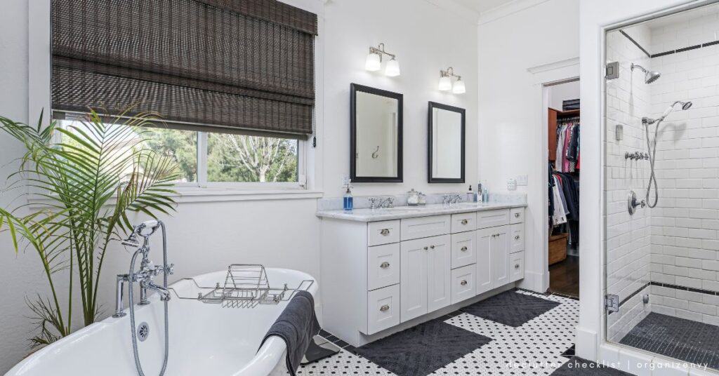 White bathroom with black and white floor tiles and separate shower and tub.