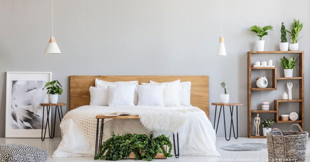 A bedroom with a large bed with wooden headboard and white bedding and plants on shelves