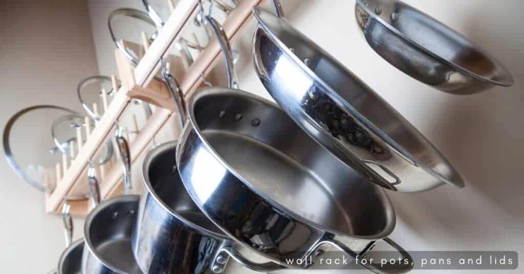 Pots and pans and lids stored on a wall rack in a kitchen