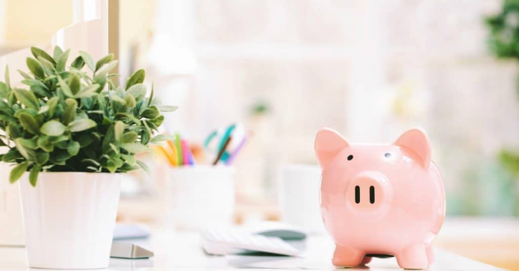 Piggy bank sitting on bright office desk, representing how to achieve financial security