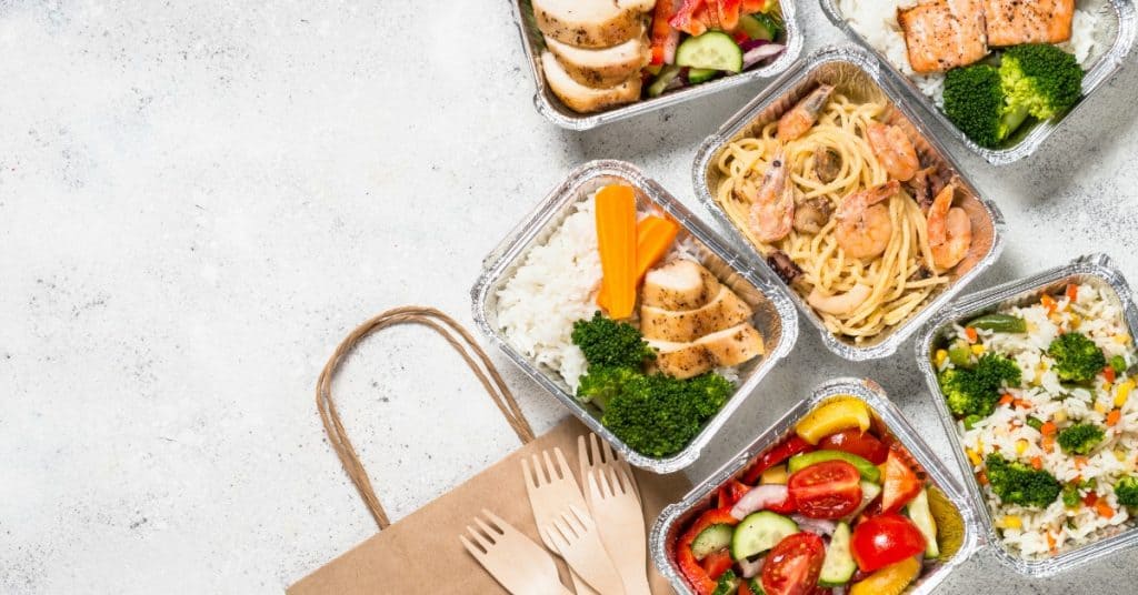 Food delivery containers laid out with forks and delivery bags