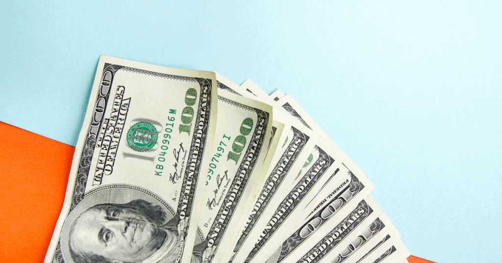 $100 bills splayed out on blue and orange background - How long to become a millionaire