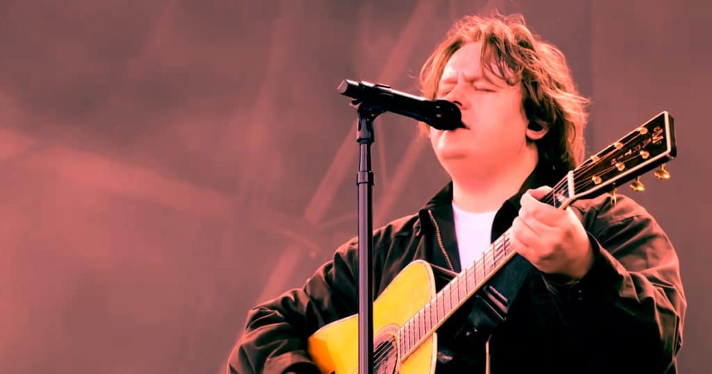 A young musician passionately singing and playing acoustic guitar at a live performance, capturing the essence of indie and singer-songwriter music genres.