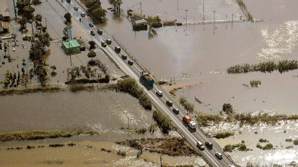 Luftaufnahme einer Küstenstraße bei Guardamar del Segura mit Fahrzeugen überflutet von Wasser in einem weiten, flachen Gelände am Mittelmeer.