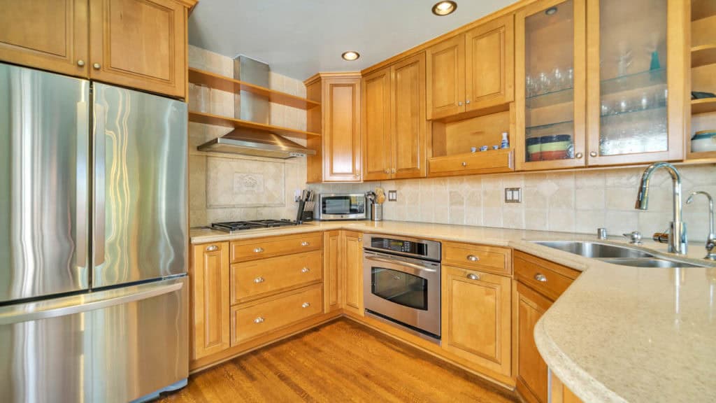 Kitchen at 2212 Myrtle Ave in North Park featuring light wood cabinetry, stainless steel appliances, a tile backsplash, and neutral stone countertops.