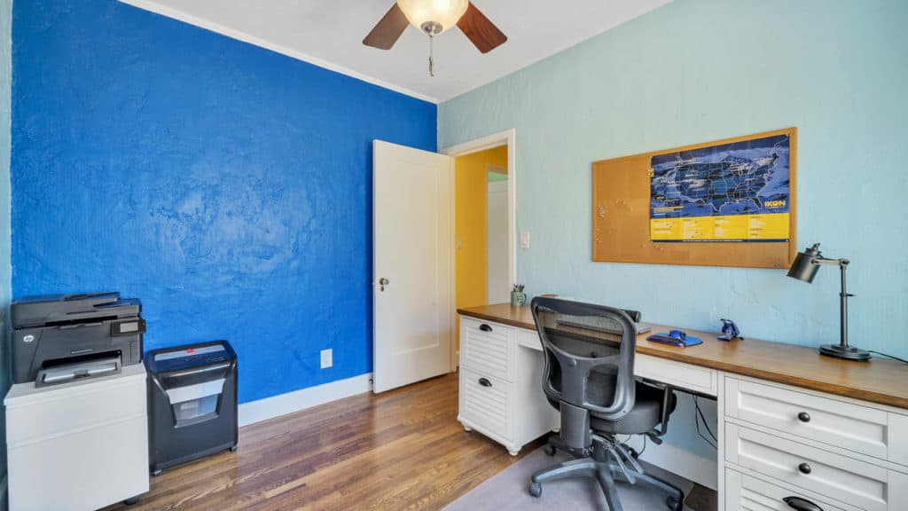 Home office at 2212 Myrtle Ave in North Park featuring a bright blue accent wall, hardwood floors, and a white desk with a wood top.