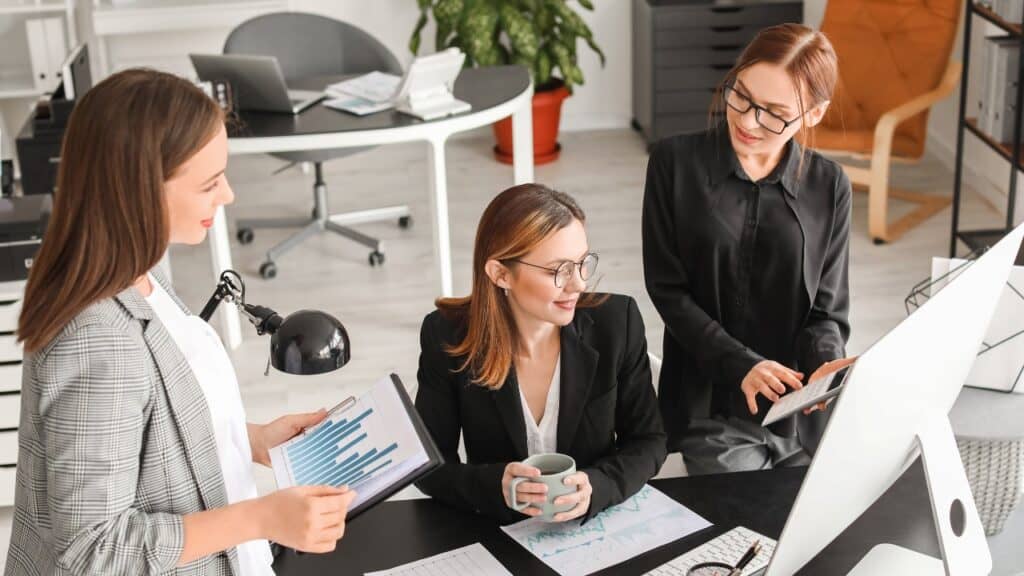 A Group of Colleagues Using a Calculator and Talking About Paperwork