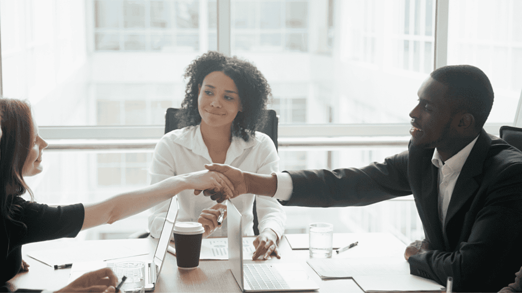 A workplace mediator overseeing two employees shaking hands