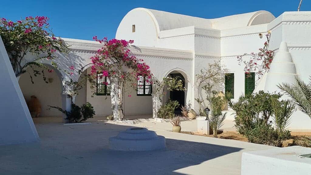 White-domed heritage house with arches and bougainvillea at the Guellala Museum in Djerba
