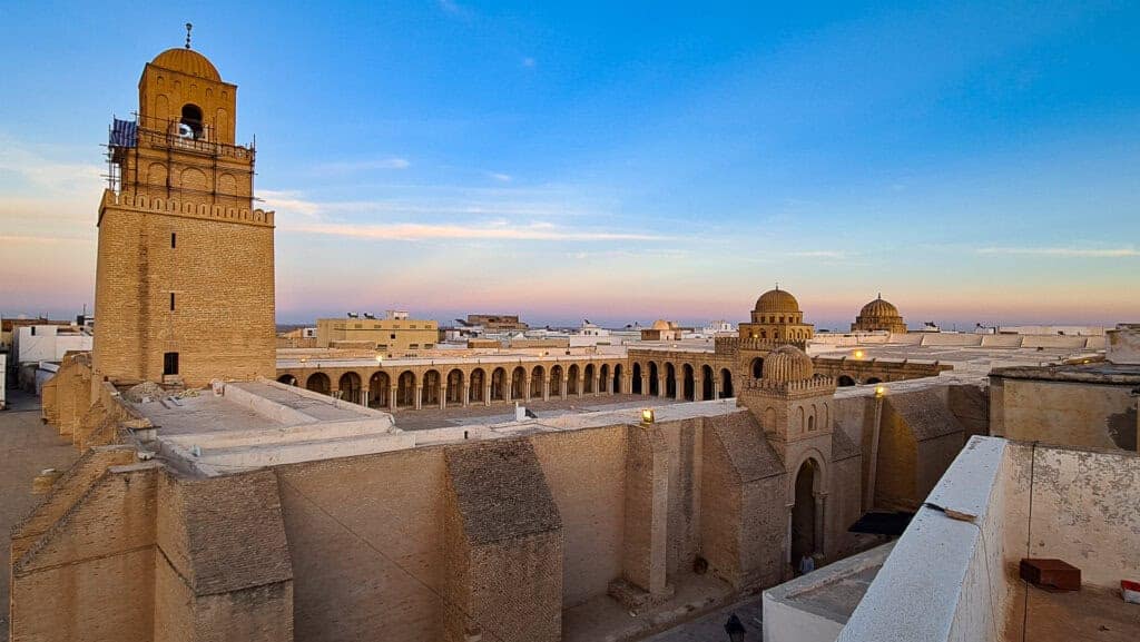 Panoramic rooftop view of the Great Mosque of Kairouan at sunset with its domes and minaret