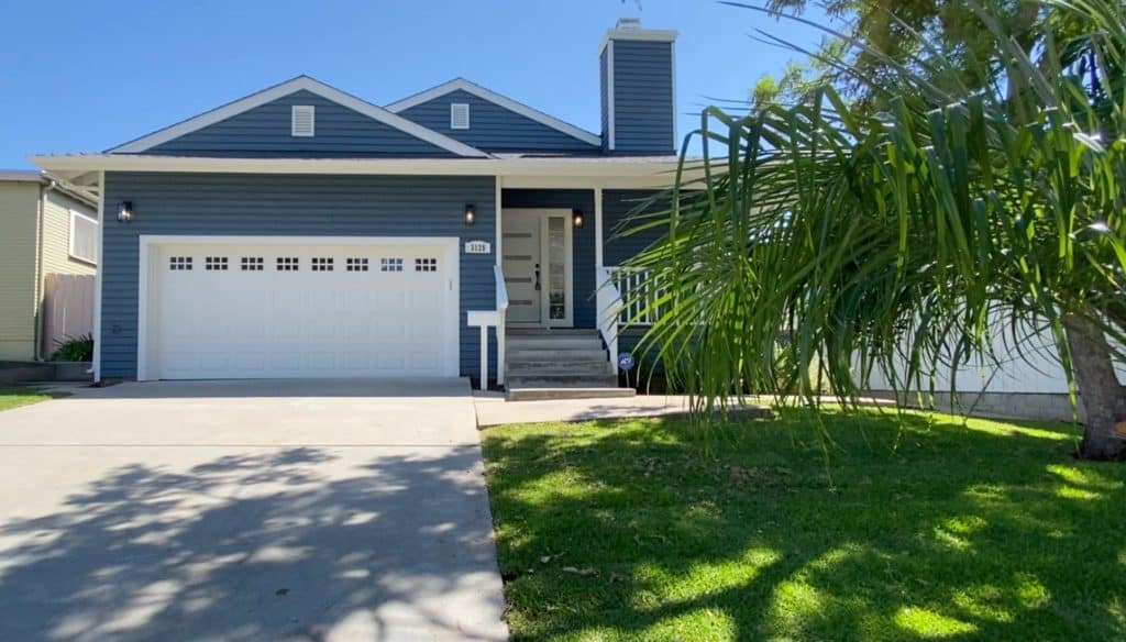 North Park San Diego home with fresh blue siding, white garage door, tidy lawn, and inviting front porch showing improved curb appeal before selling