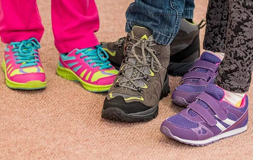three kids showing off sports shoes
