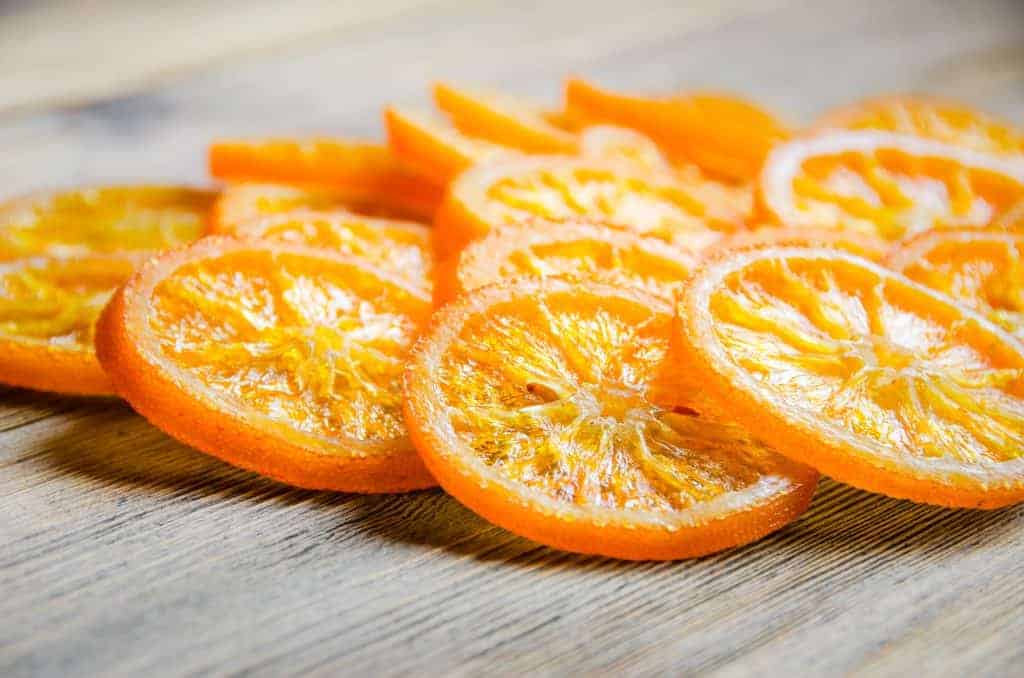 Sliced candied oranges on wooden table, selective focus