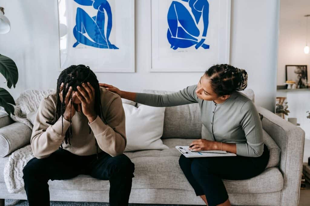 A Person Comforting Someone Who Looks Stressed in a Grey Sofa