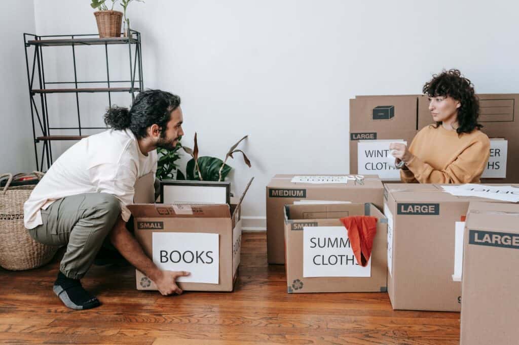 A Couple Packing Up Boxes With Labels