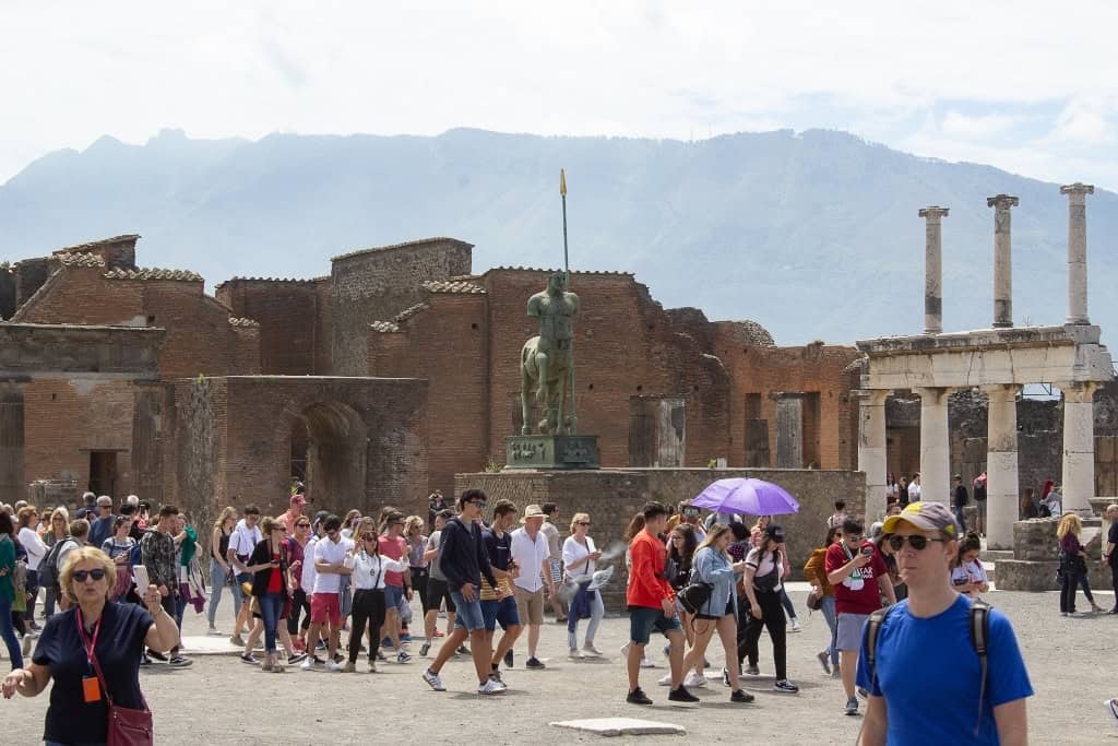 Tourists admiring the bronze Centaur statue in the Forum of Pompeii, a popular photography spot.