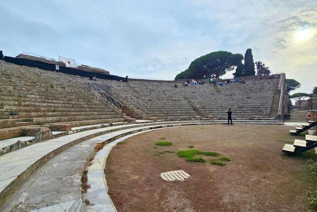 Ancient Roman amphitheater at Ostia Antica viewed from the stage, showing curved stone seating, part of the archaeological ruins near Rome, Italy.