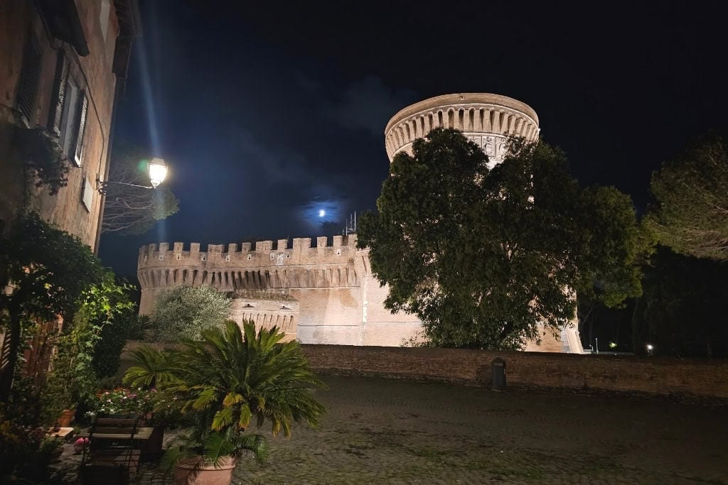Julius Castle (Castello di Giulio II) at night in Ostia Antica, Italy, illuminated under the moonlight. This medieval fortress is one of the top things to see in the ancient village of Ostia Antica after visiting the archaeological park. A magical and lesser-known Rome day trip destination.