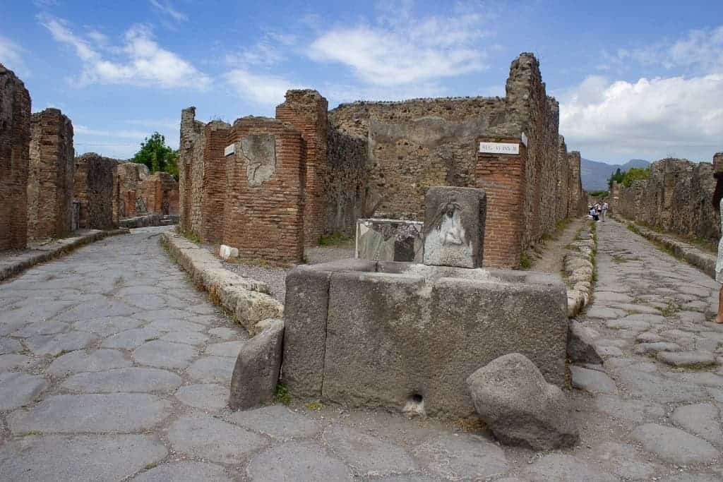 Stone fountain at a street crossroads in Pompeii, highlighting Roman engineering.