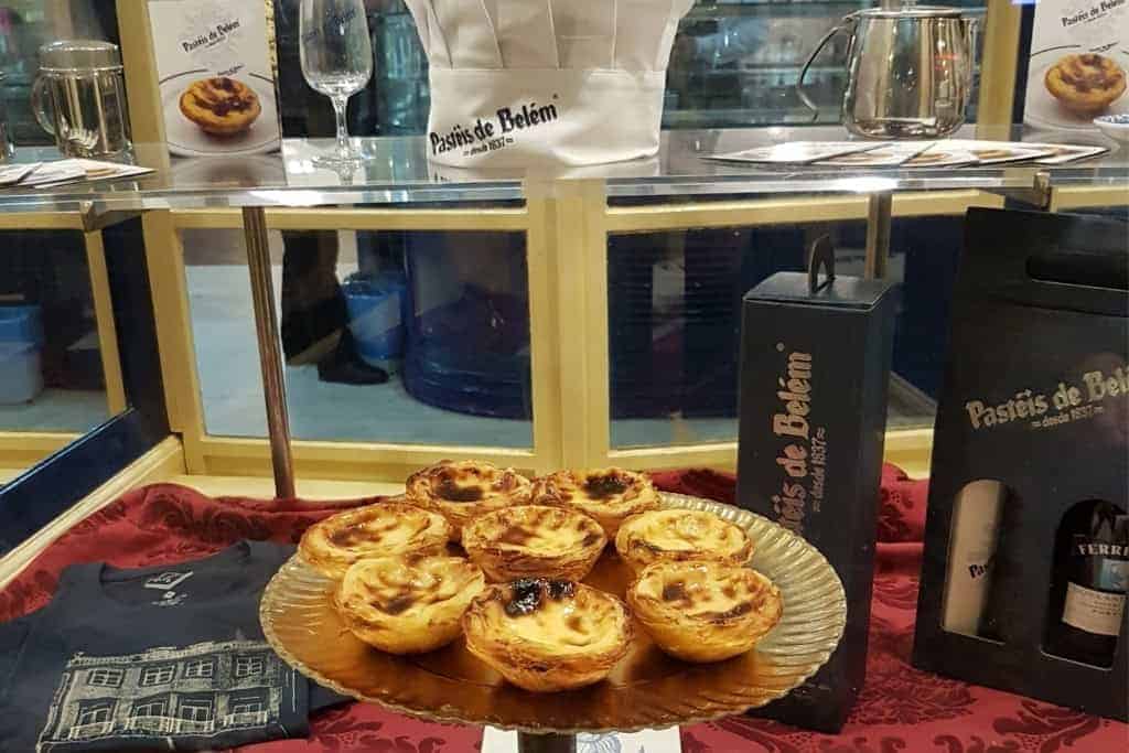 Freshly baked Pastéis de Belém custard tarts showcased in a Lisbon bakery window—an iconic sweet treat that makes a delicious edible souvenir from Portugal.