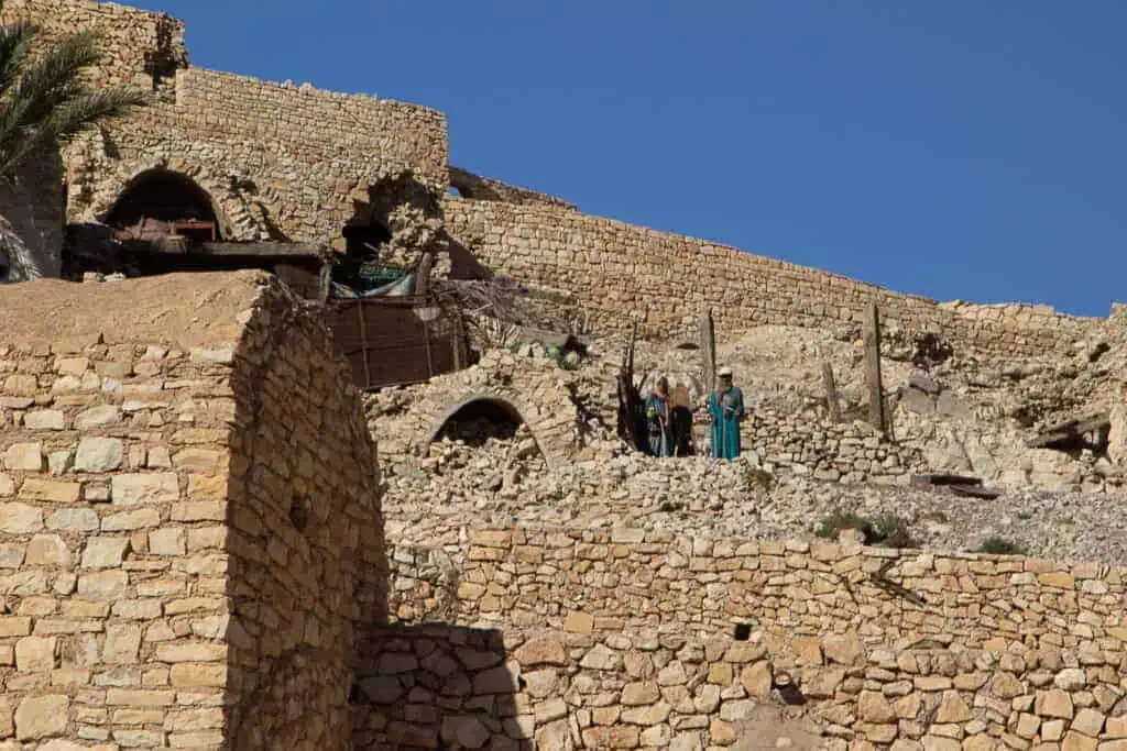 View of the hillside village of Beni Zelten in southern Tunisia with stone architecture and locals in traditional dress